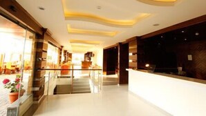 A hotel lobby with a modern design, featuring a glass partition, a reception desk, and a staircase leading to upper floors. - Hotel Le Noble (Zouk El Kharab)