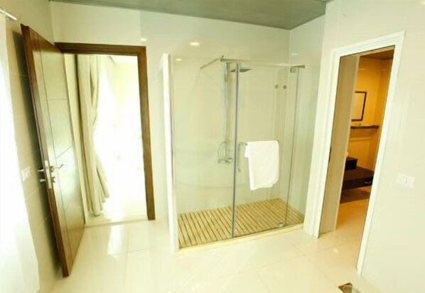 Un baño moderno con cabina de ducha de vidrio, un perchero visible y una puerta que da a otra habitación.