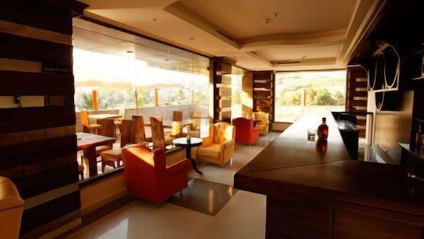 A modern hotel lobby with a spacious seating area, large windows offering a view of the outdoors, and a bar area. - Hotel Le Noble (Zouk El Kharab)