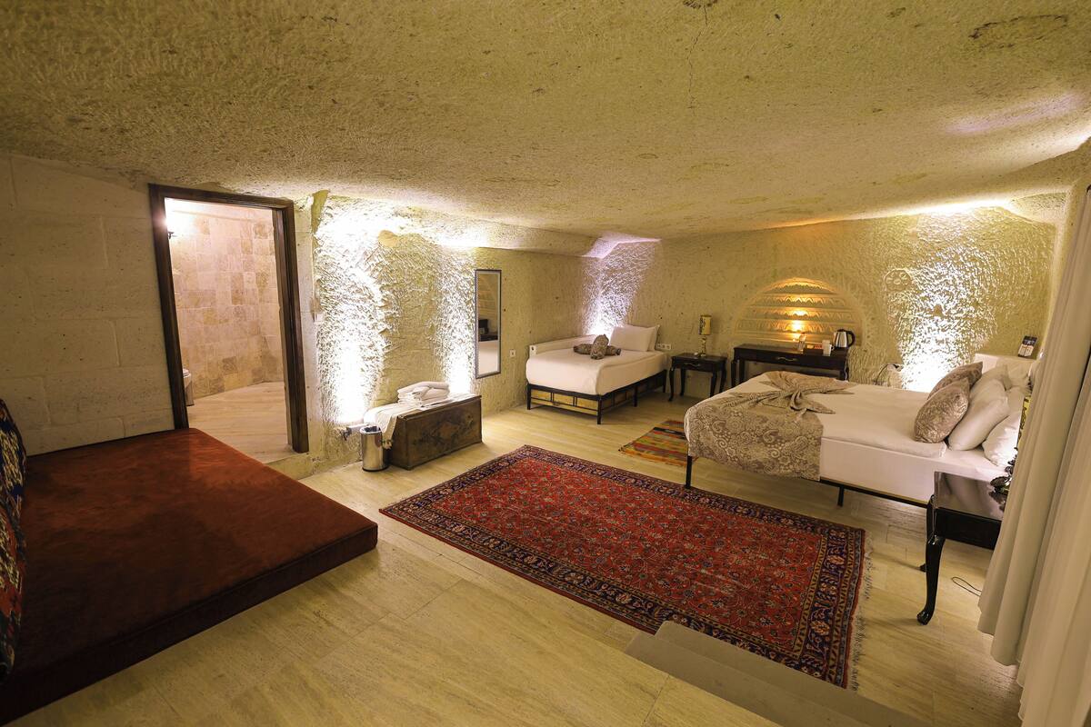 A bedroom with a bed, a sofa, a small table, and a rug.