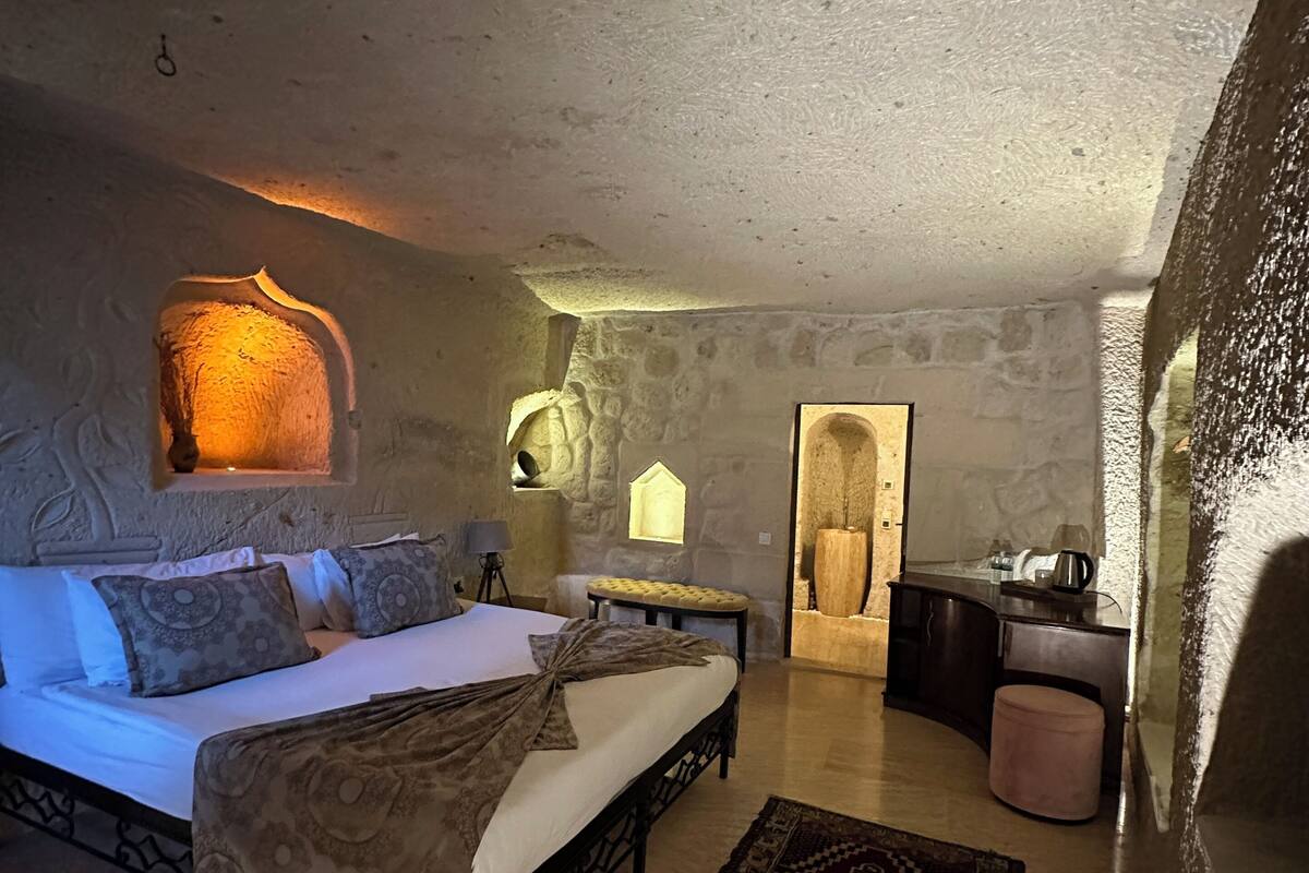 A bedroom with a bed, bedside table, lamp, and a rug.