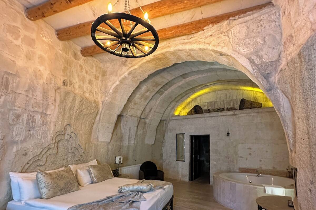 A stone-walled bedroom with a bed, a small table, and a bathtub.