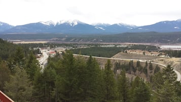 A mountainous landscape with a town in the valley, featuring a mix of residential and commercial buildings, a road, and a body of water.