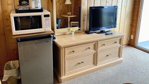 Uma cozinha compacta equipada com micro-ondas, frigorífico e uma pequena mesa com candeeiro.