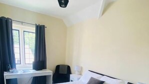 A hotel room with a large bed, a desk, and a chair. - The Mirfield Monastery (Mirfield)