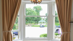 A room with a bay window, two chairs, a table, and a chandelier. - Steeton Hall Hotel (Keighley)