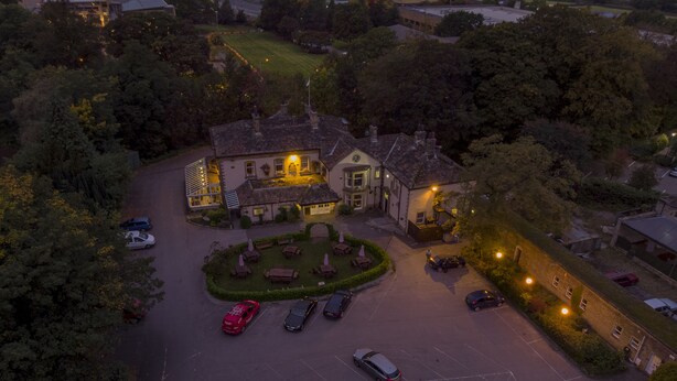 An aerial view of a hotel with a courtyard, multiple parking spaces, and surrounding greenery. - Steeton Hall Hotel (Keighley)