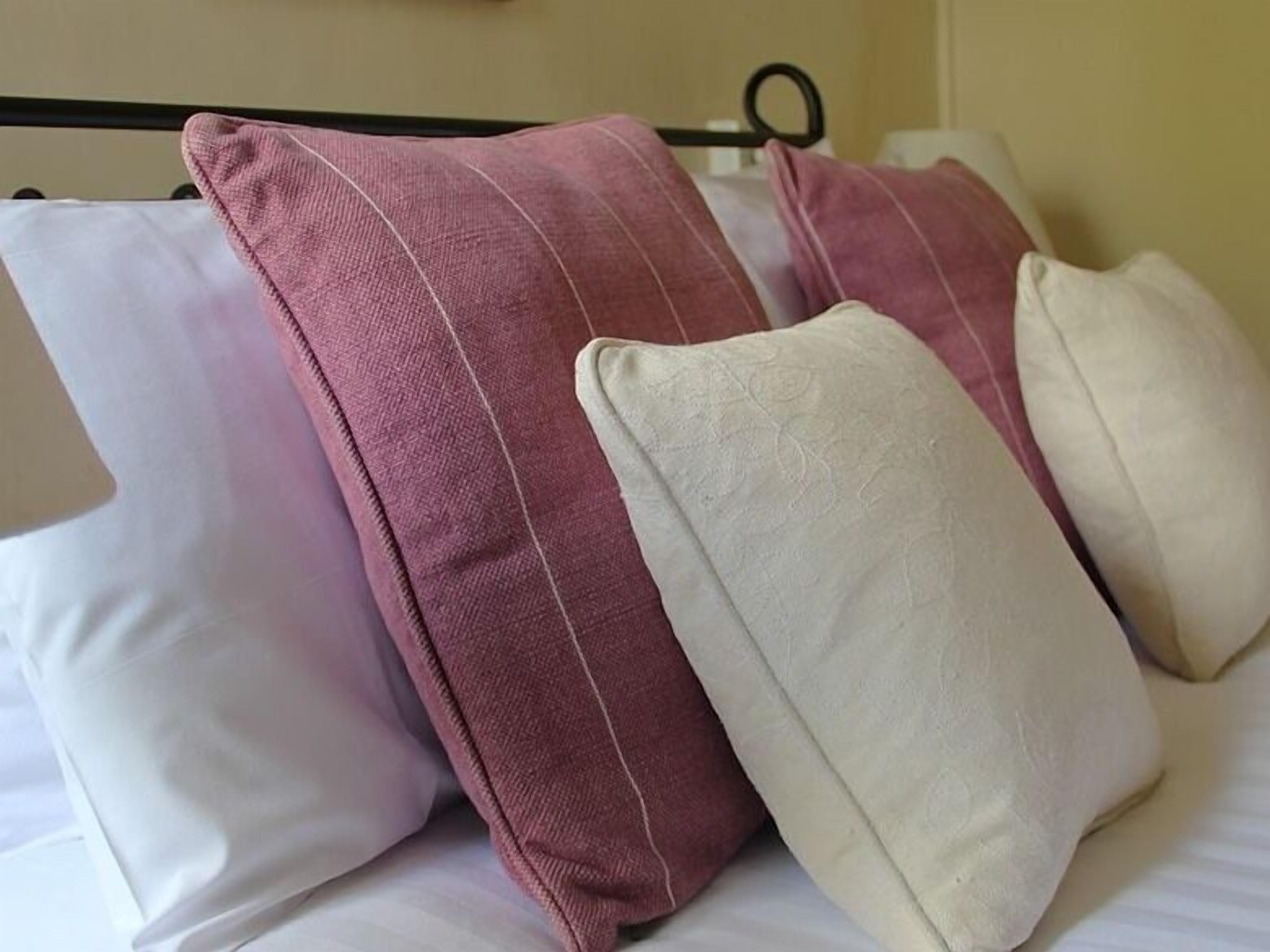 A bed with white and pink pillows.