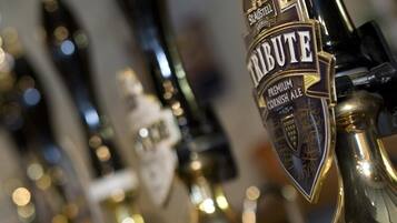 A close-up of a beer tap labeled "Tribute Premium Cornish Ale" with a gold and black design.