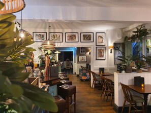 A restaurant interior with wooden tables, chairs, hanging pendant lights, and framed artwork on the walls. - The White Horse (Maldon)
