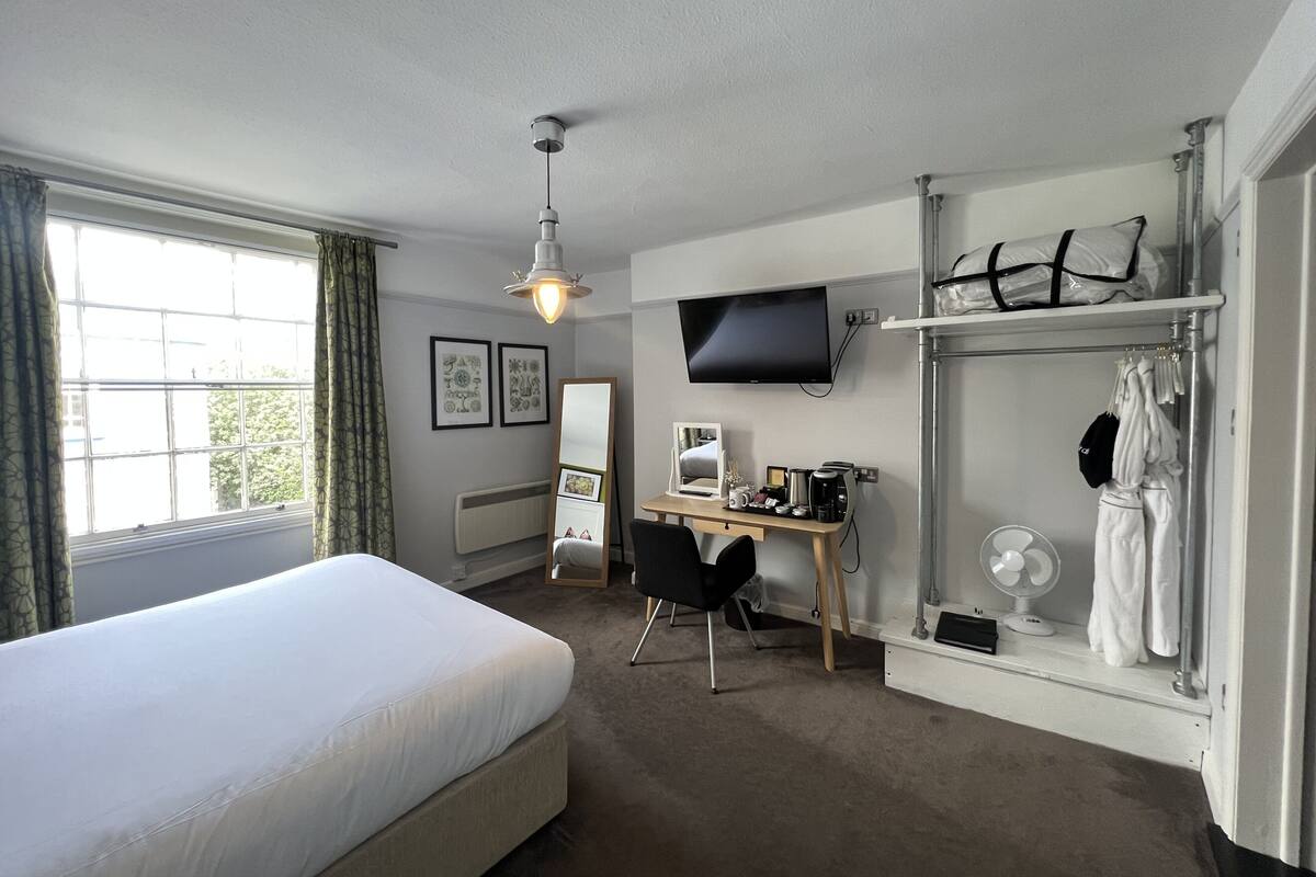 A hotel room with a bed, desk, chair, TV, and a walk-in closet.