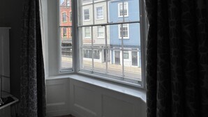A room with a large window, a wooden floor, and a view of buildings outside. - The White Horse (Maldon)