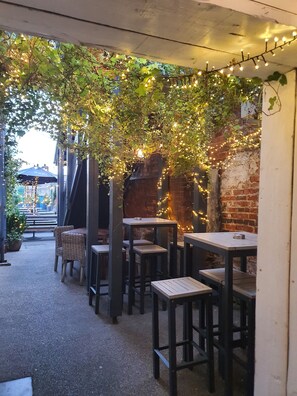 An outdoor seating area with tables and chairs, string lights, and greenery. - The White Horse (Maldon)