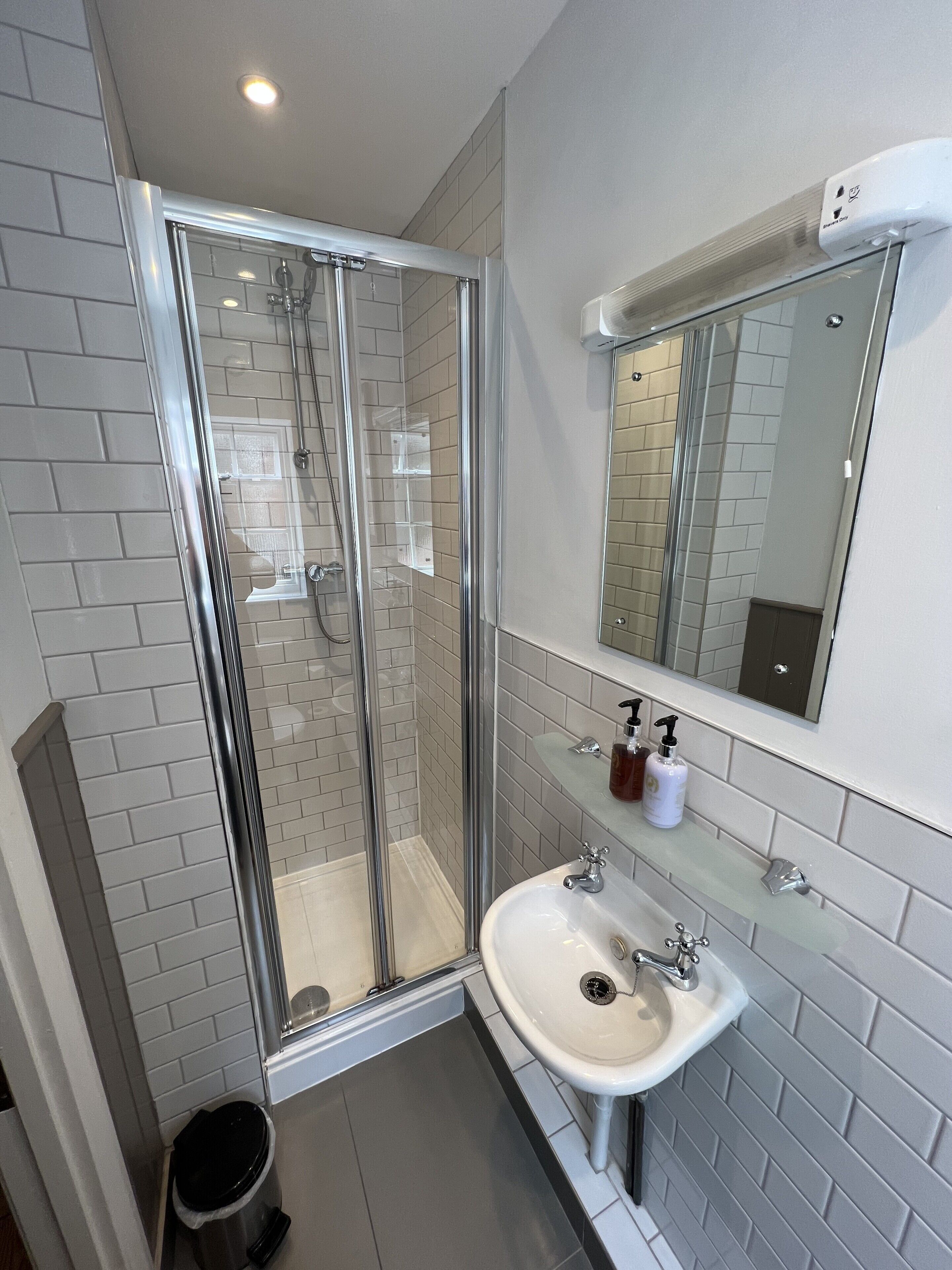 A modern bathroom with a glass-enclosed shower, a white sink, and a mirror above the sink.