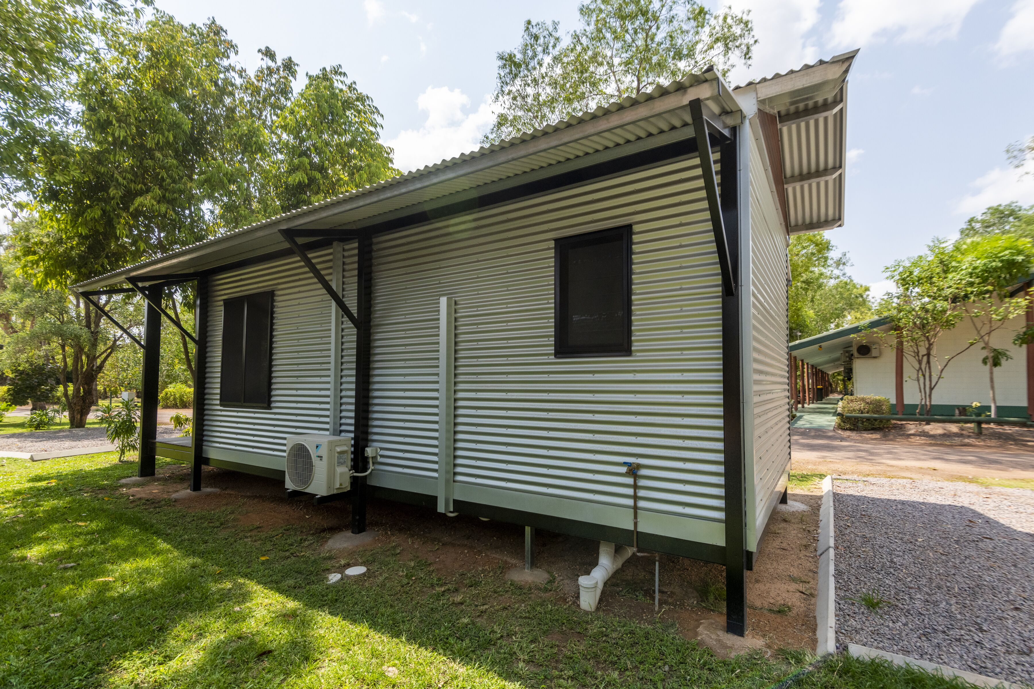 A single-story mobile home with a metal exterior, a covered porch, and a small attached garage.