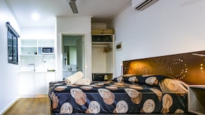Un dormitorio con cama, mesita de noche y ventilador de techo.