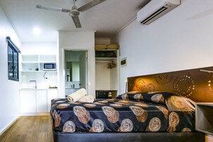 A bedroom with a bed, bedside table, and a ceiling fan.