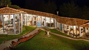 A two-story building with a tiled roof, large glass windows, and a central courtyard. - Dantica Cloud Forest Lodge (Copey)