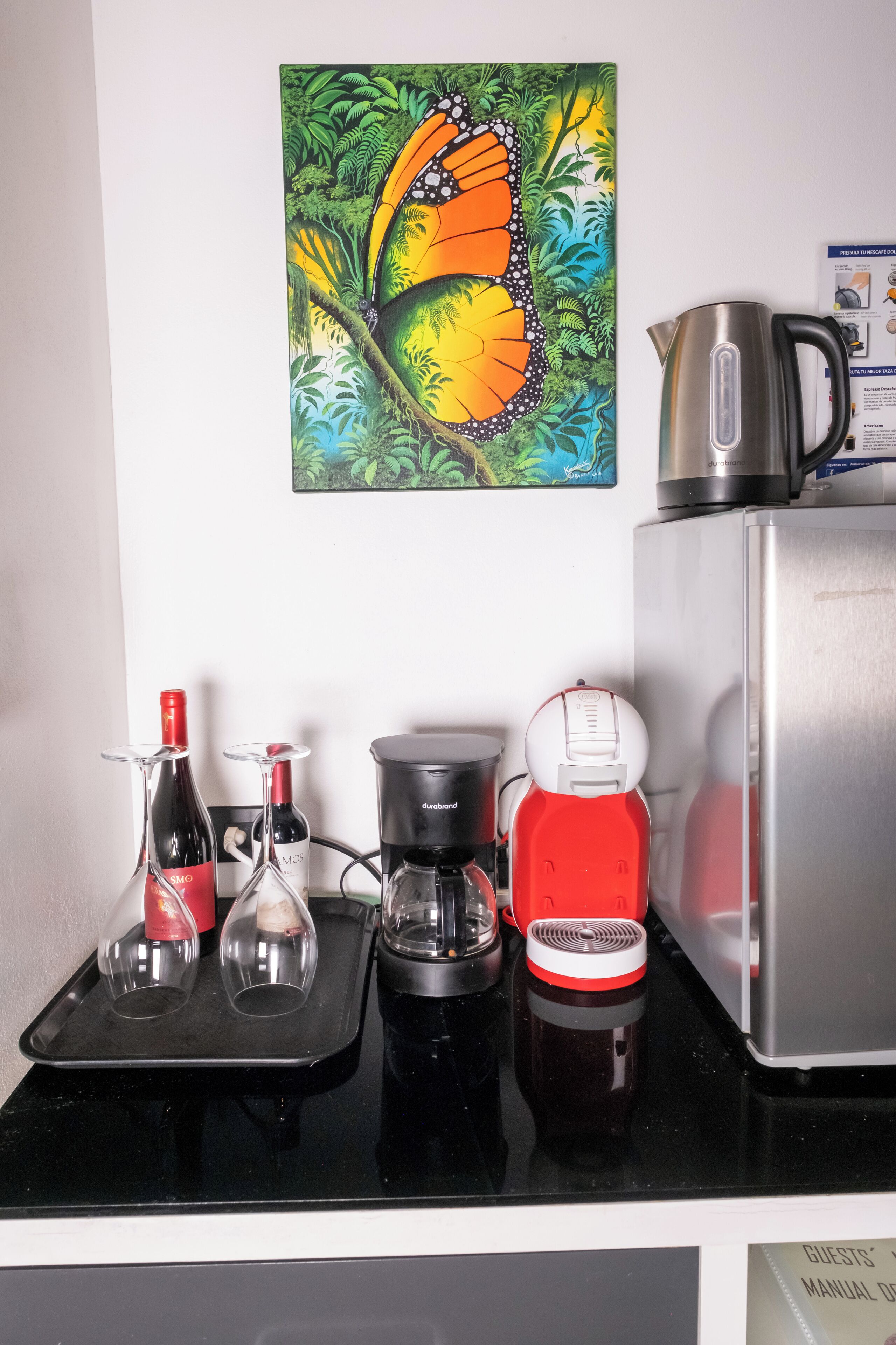 A kitchen counter with a coffee maker, a kettle, and a wine bottle.