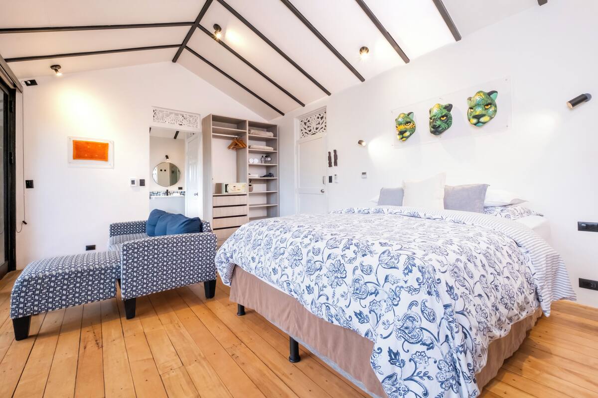 A bedroom with a large bed, two smaller beds, a wardrobe, and a mirror.