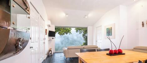 Un comedor moderno con una mesa de madera, sillas negras y vistas al exterior.
