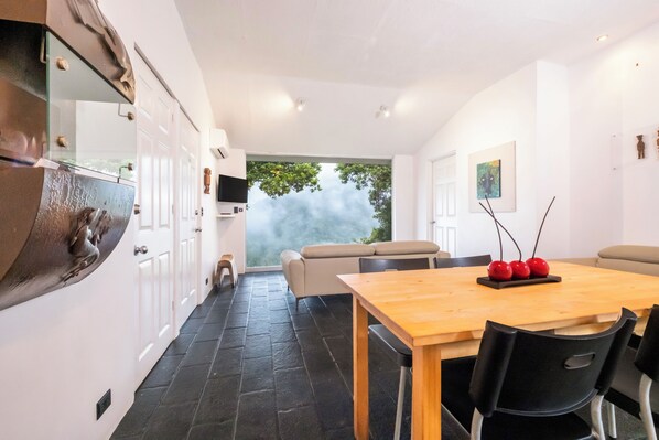 Un comedor moderno con una mesa de madera, sillas negras y vistas al exterior.