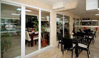 Un vestíbulo de hotel con zona de comedor, bar y mostrador de recepción.