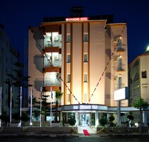Un hotel con un letrero llamativo que dice "Lara Diamond Hotel" en la entrada, con una alfombra roja que lleva a la puerta.