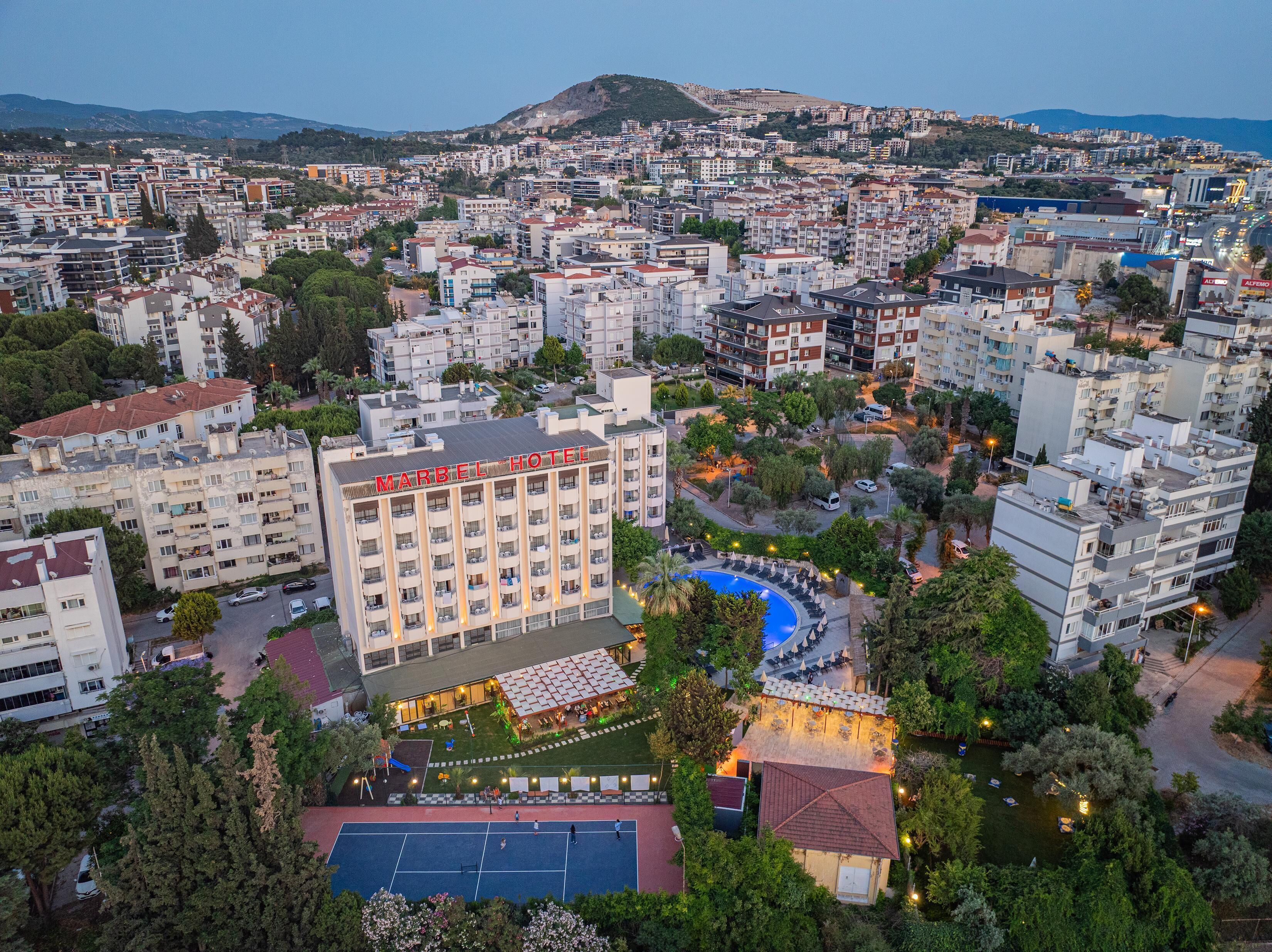 A hotel with multiple floors, outdoor pool, and tennis court.