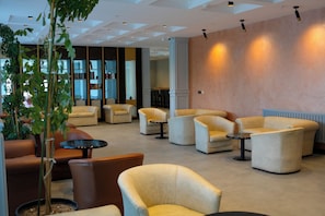 Un espace détente moderne avec des canapés, des fauteuils et une petite table.
