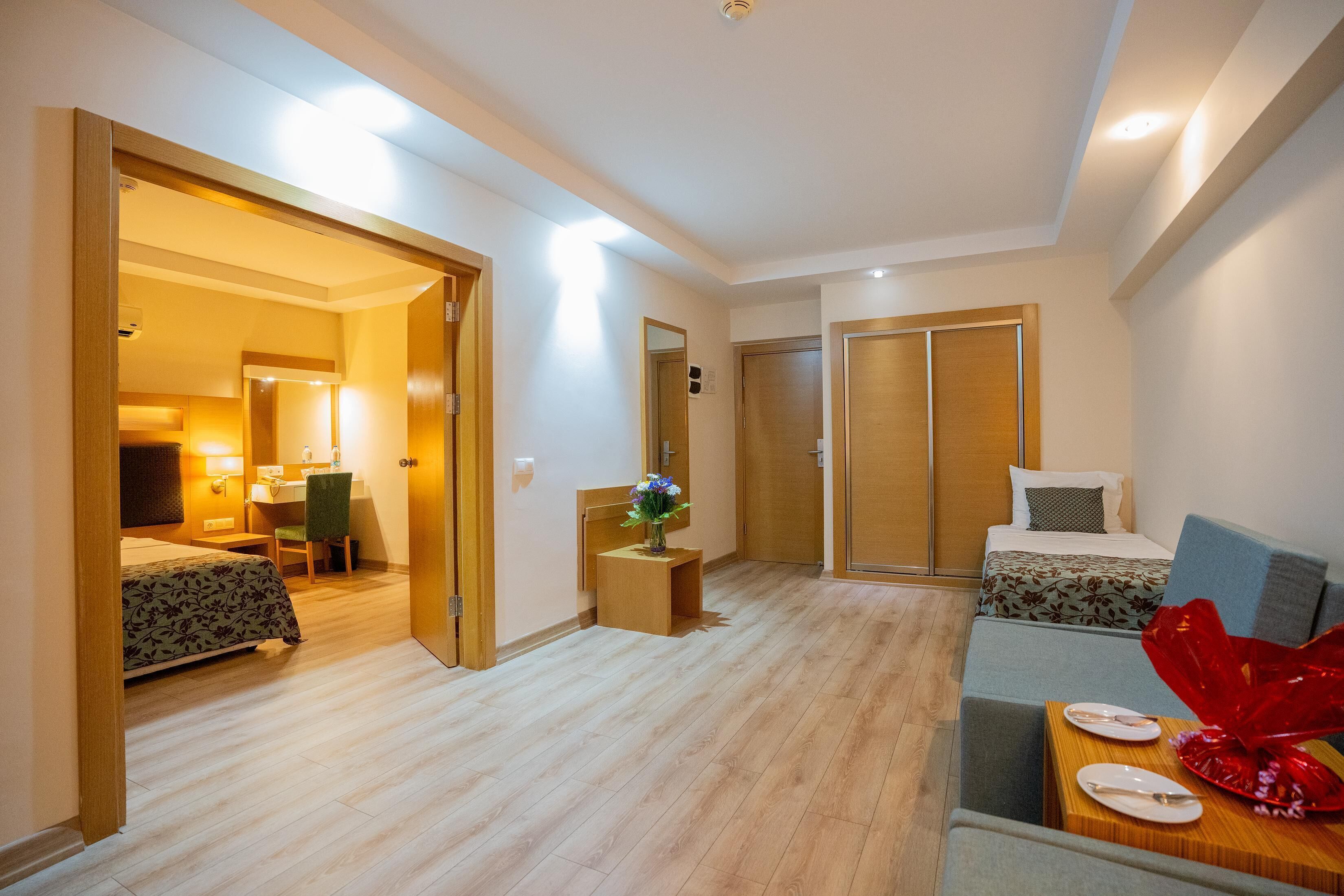 A hotel room with a bed, a desk, a chair, and a small table with a red decorative item.