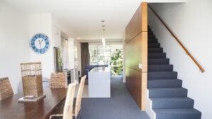Un interior moderno con comedor, una escalera y vistas al exterior.