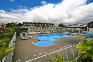 Una piscina al aire libre, sillones reclinables de piscina