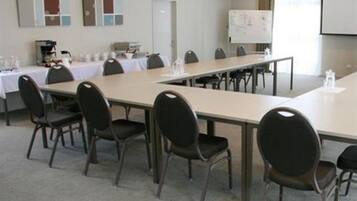 A conference room with a long table, chairs, a whiteboard, and a projector screen.