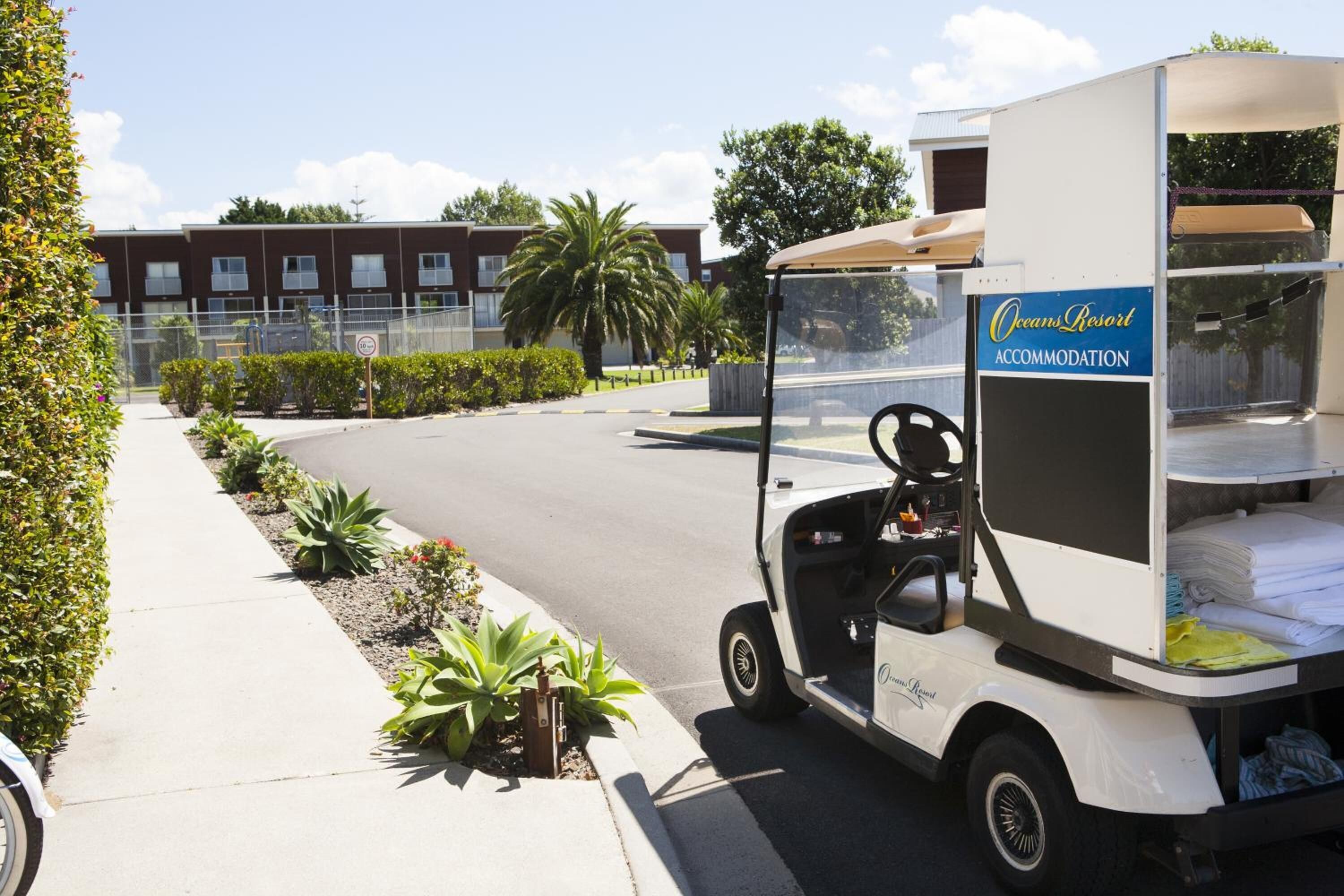 A golf cart with a sign for Oceans Resort Accommodation parked on a street.