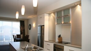 Una cocina moderna con una isla central, electrodomésticos de acero inoxidable e iluminación colgante.