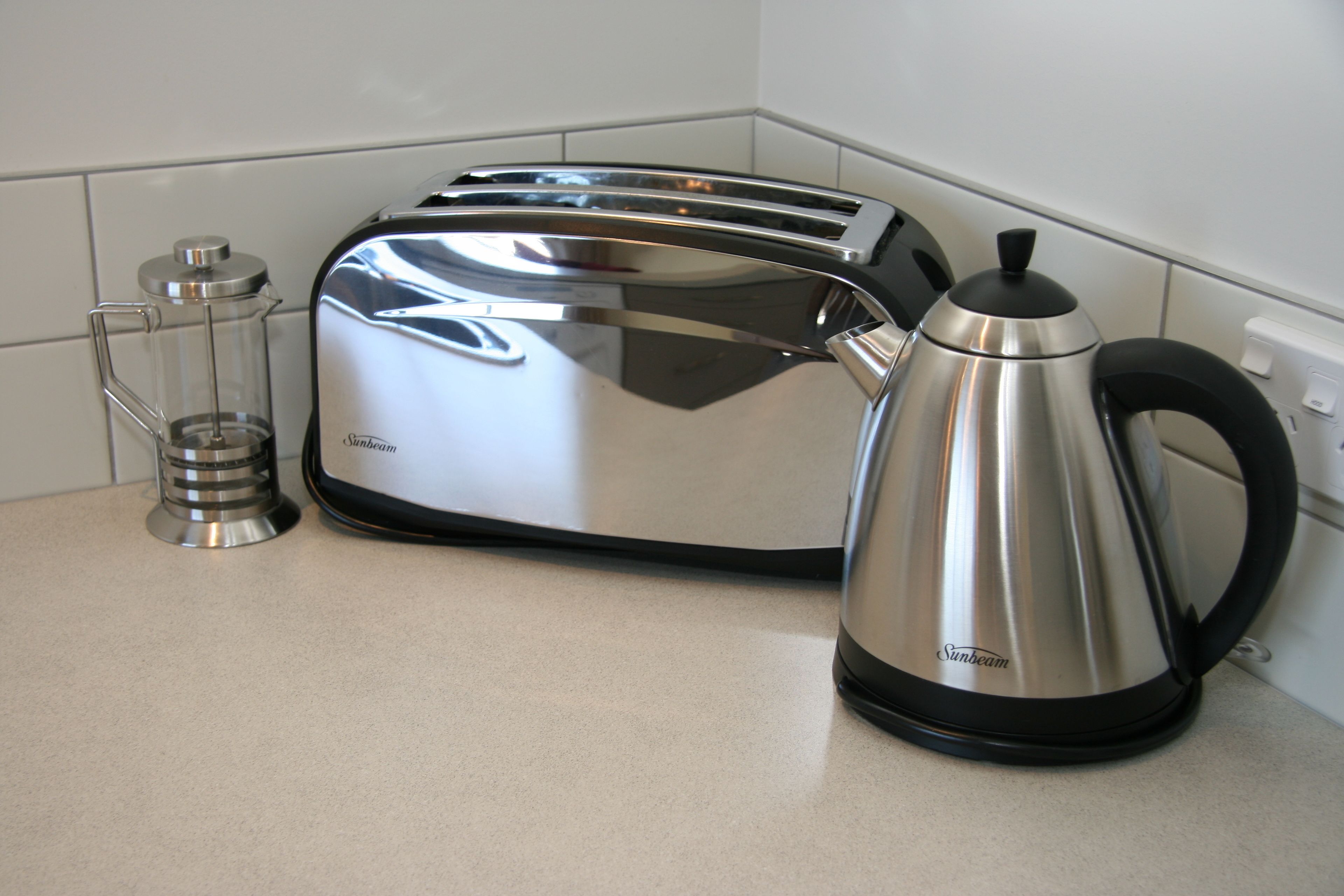 Un tostador de acero inoxidable y una cafetera Sunbeam sobre una encimera de cocina.