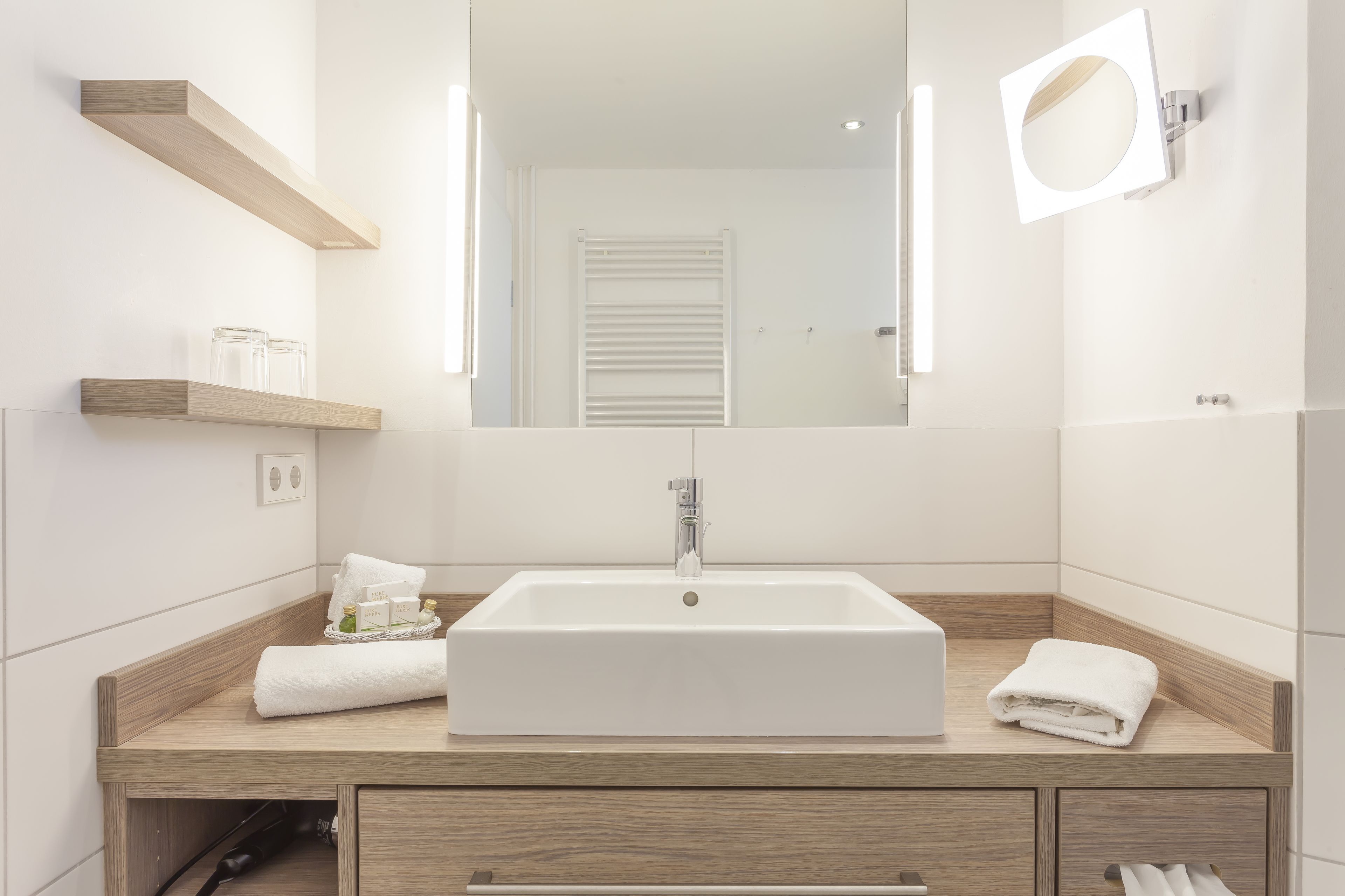 A modern bathroom with a rectangular sink, wooden countertop, and built-in shelves.