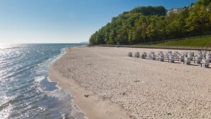 A beach with rows of empty beach chairs and a fence along the water's edge. - Hotel Bernstein (Sellin)