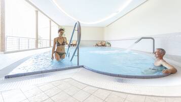 Piscina interior con vista despejada al área de la piscina, un puesto de salvavidas y una zona de estar con sillones reclinables.