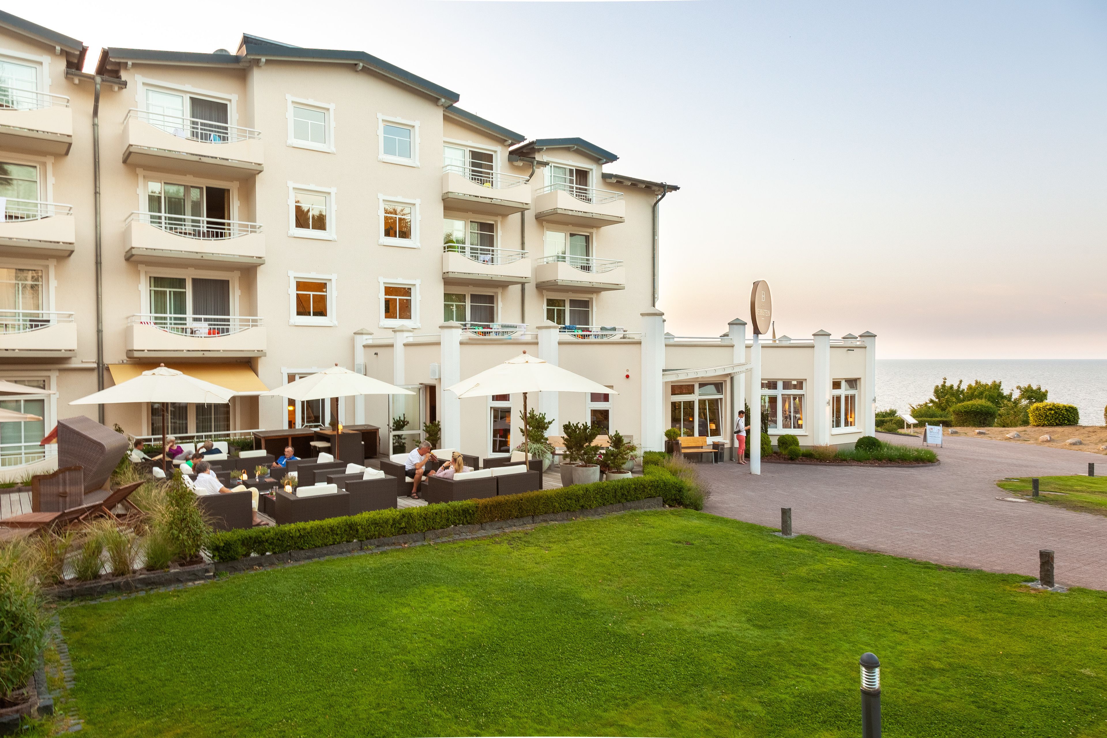 Un hotel de varios pisos con zonas de estar al aire libre, piscina y vistas al mar.