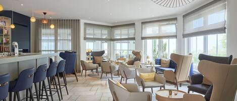 A modern hotel lobby with a bar area, seating arrangements, and large windows.
