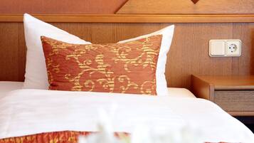 A hotel room with a bed, a nightstand, a lamp, and a power outlet.