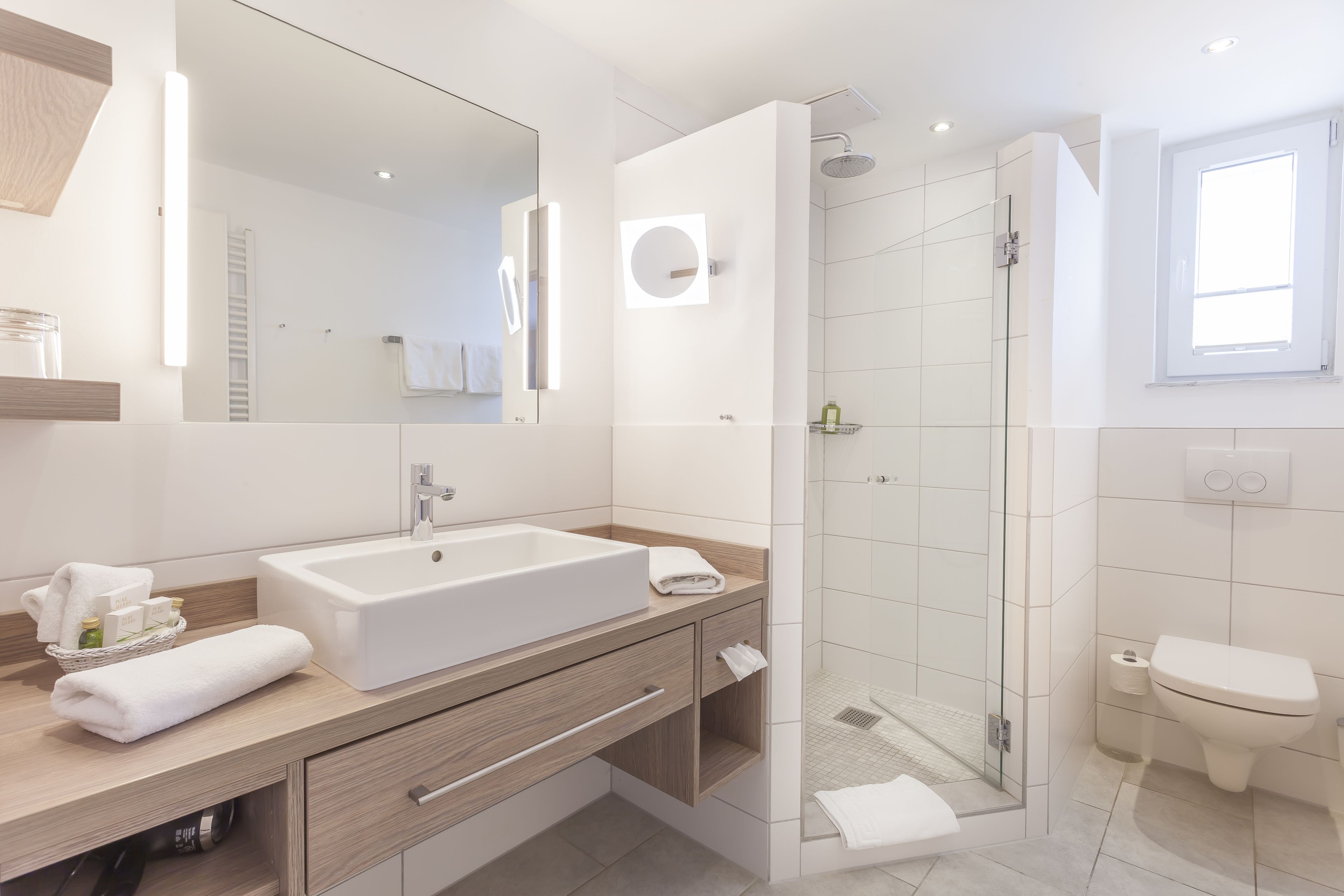 A modern bathroom with a large sink, mirror, and shower.