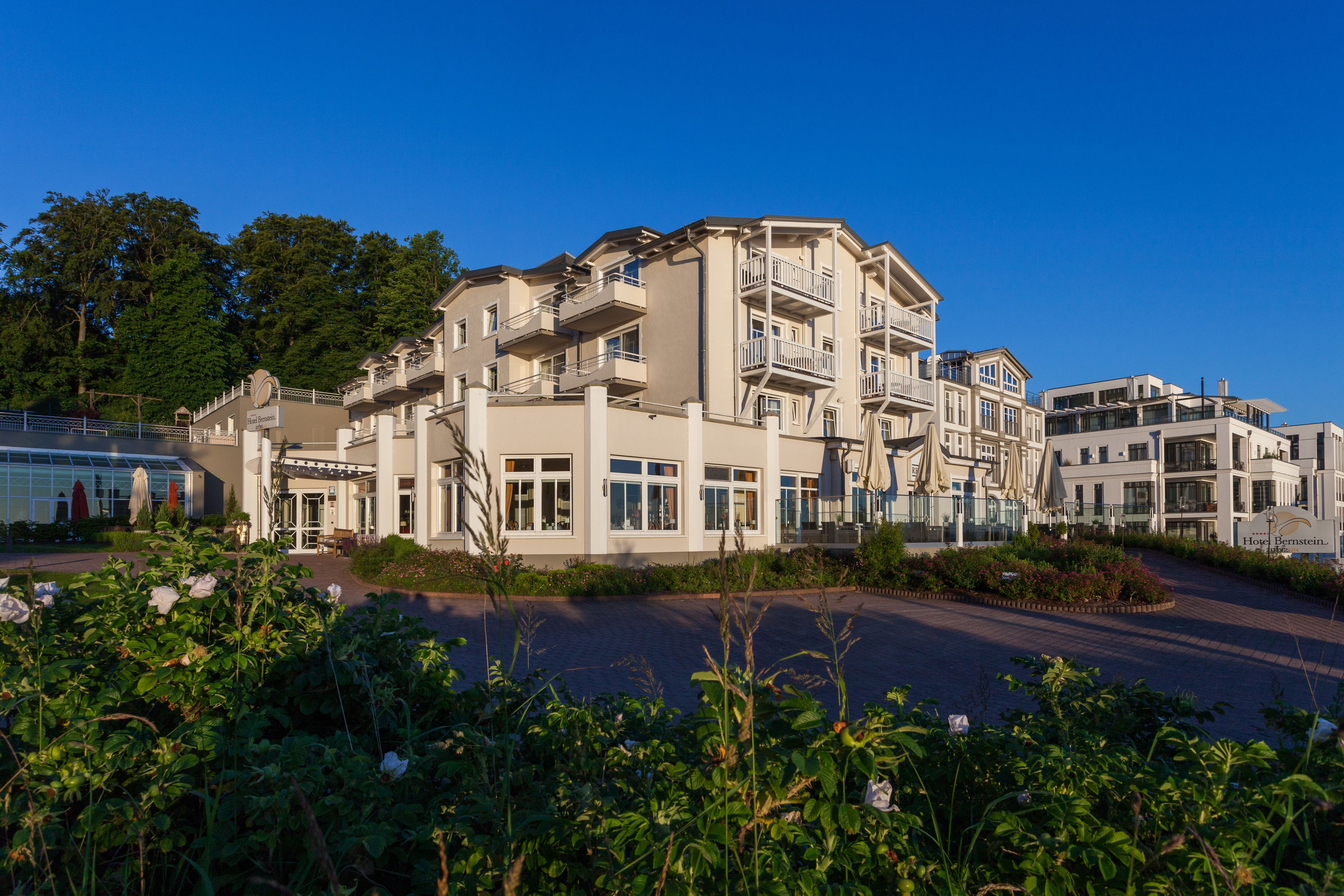 Un hôtel à plusieurs étages doté de balcons, d’une entrée principale et d’un jardin aménagé.