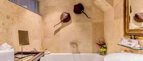 A modern bathroom with a bathtub, a large mirror, and two decorative fish mounted on the wall.