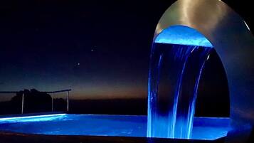 Vue nocturne d’une installation aquatique agrémentée d’une structure arquée métallique.