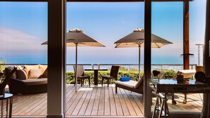 Una terraza con asientos al aire libre, sombrillas y vista al mar.