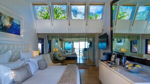 Un dormitorio amplio con una cama grande, un escritorio y vistas al exterior a través de tragaluces.