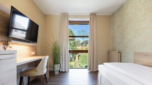 A bedroom with a bed, a desk with a chair, a television, and a window with curtains. - Hotel Engel (Hamburg)